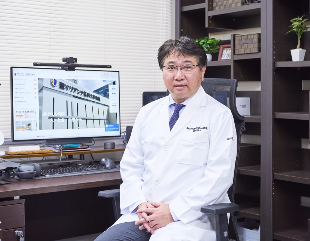 執務室で椅子に座りこちらを見る民上教授 スマホ版画像